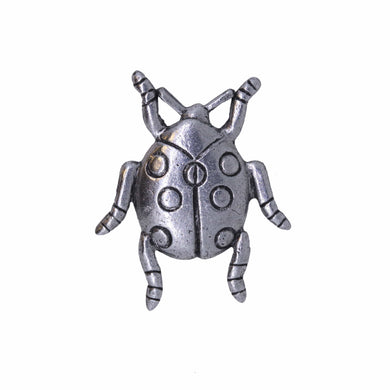 Silver beetle-shaped ladybug pin on a white background
